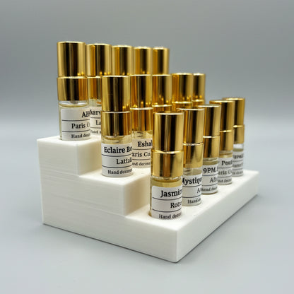 Set of small bottles with gold caps on a white stand against a light gray background